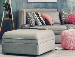 Grey ottoman and couch in room with pink decorative accents