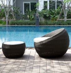 Black weave chairs with white cushions in front of outdoor pool